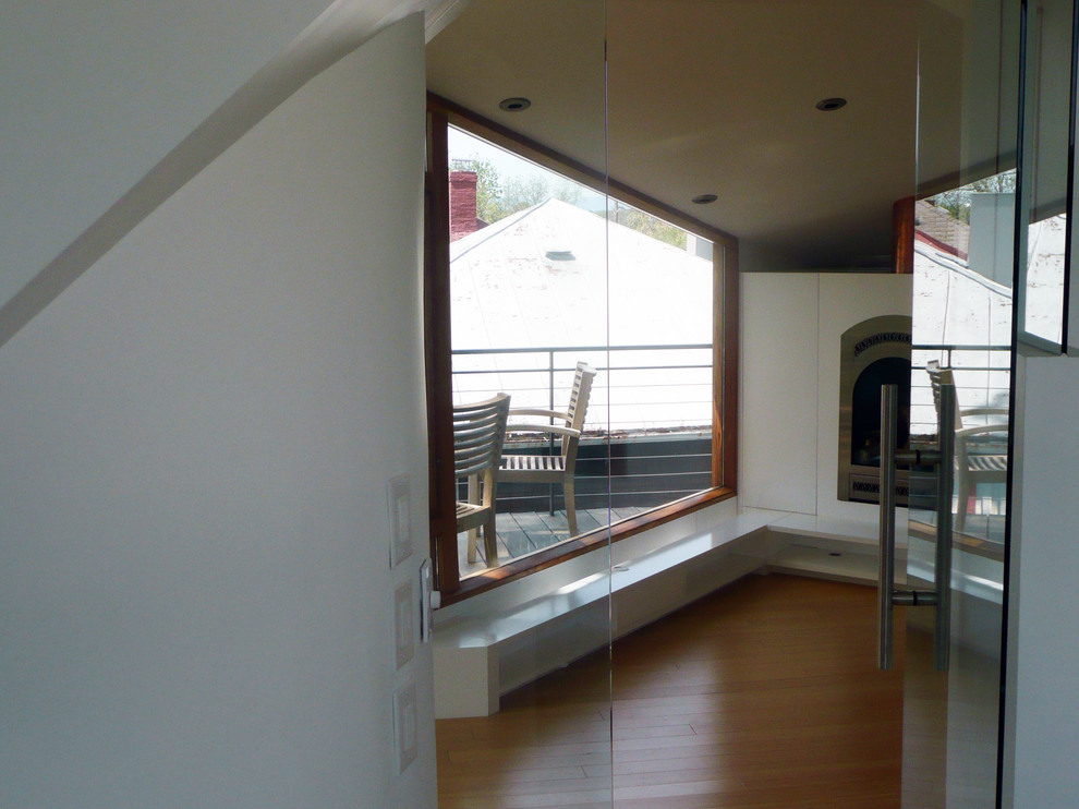 Example of a small trendy master light wood floor home design design with white walls and a wood stove