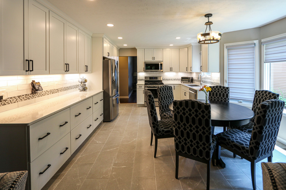 Mid-sized transitional u-shaped eat-in kitchen in Cleveland with an undermount sink, recessed-panel cabinets, white cabinets, quartz benchtops, white splashback, porcelain splashback, stainless steel appliances, porcelain floors, no island, grey floor and white benchtop.