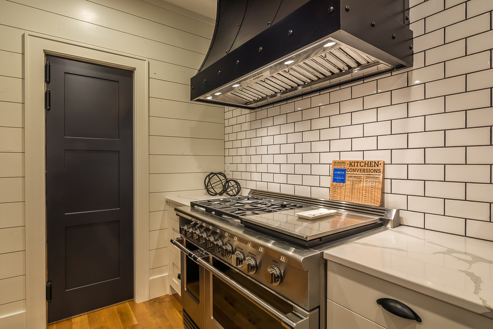 Eat-in kitchen - large transitional galley medium tone wood floor eat-in kitchen idea in Cedar Rapids with a farmhouse sink, shaker cabinets, beige cabinets, marble countertops, white backsplash, subway tile backsplash, stainless steel appliances and an island