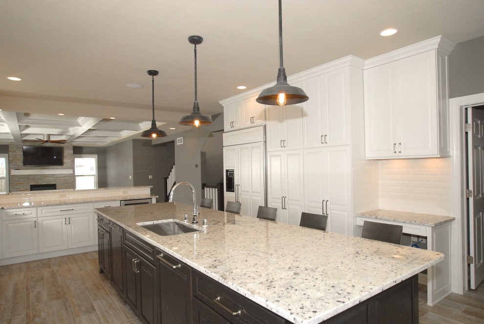 Eat-in kitchen - large transitional galley porcelain tile and beige floor eat-in kitchen idea in Milwaukee with an undermount sink, raised-panel cabinets, white cabinets, granite countertops, white backsplash, subway tile backsplash, stainless steel appliances and an island
