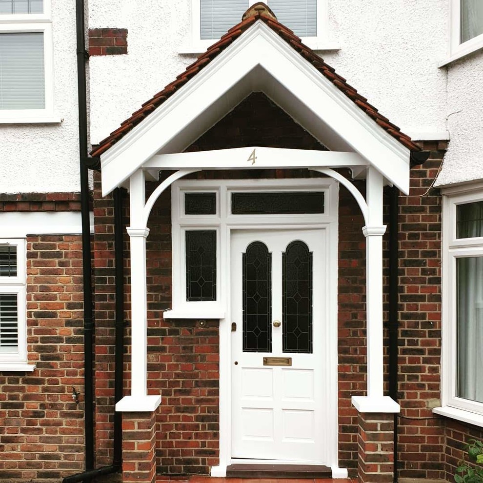Design ideas for a mid-sized traditional front door in London with red walls, concrete floors, a single front door, a white front door, grey floor, recessed and brick walls.