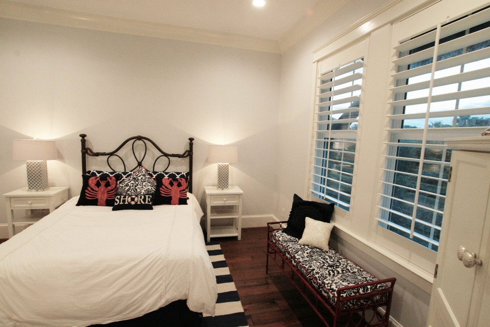 Photo of a large beach style guest bedroom with grey walls, dark hardwood floors and no fireplace.