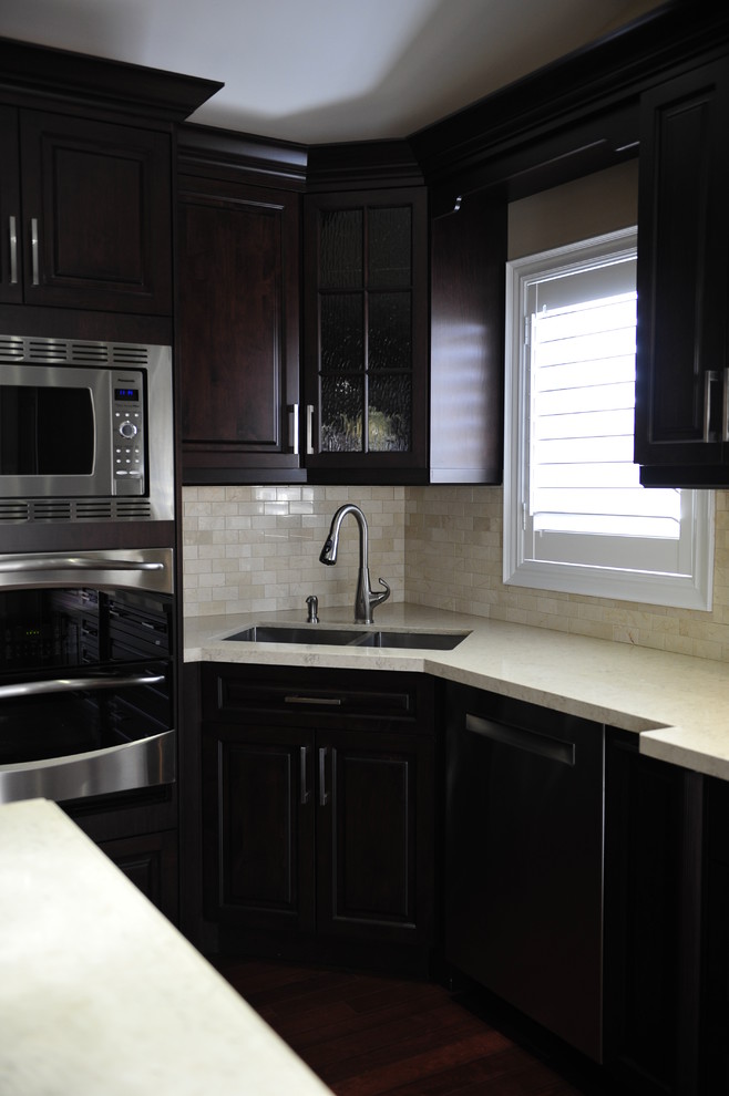 Inspiration for a mid-sized transitional u-shaped eat-in kitchen remodel in Toronto with a double-bowl sink, raised-panel cabinets, dark wood cabinets, quartz countertops, multicolored backsplash, matchstick tile backsplash, stainless steel appliances and a peninsula