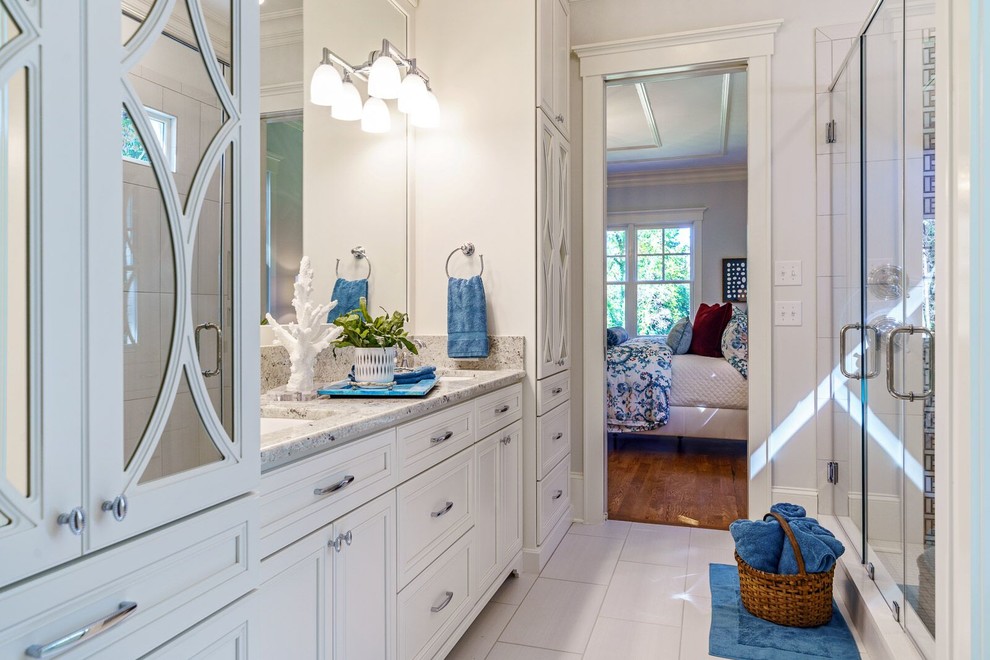 Large master bathroom in Other with louvered cabinets, white cabinets, a corner shower, white walls, porcelain floors, an undermount sink, granite benchtops, white floor, a hinged shower door and multi-coloured benchtops.