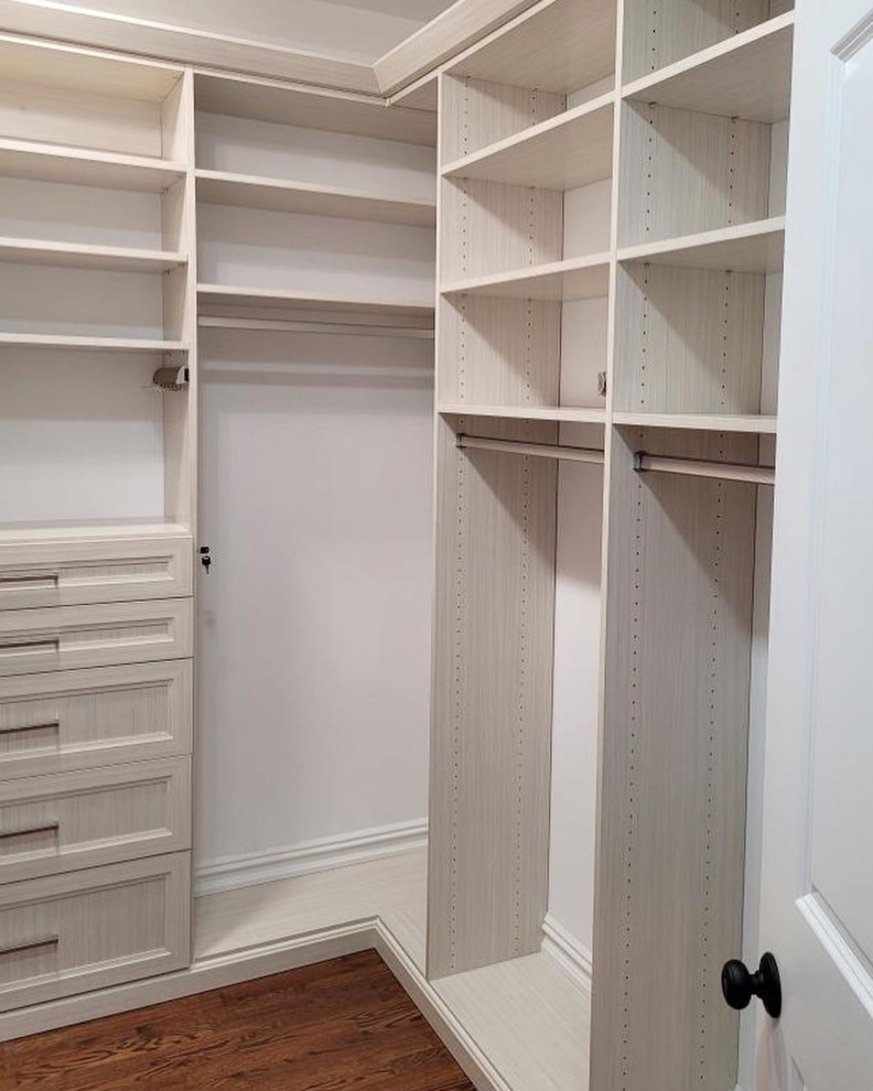 Mid-sized elegant gender-neutral dark wood floor and brown floor walk-in closet photo in New York with recessed-panel cabinets and beige cabinets