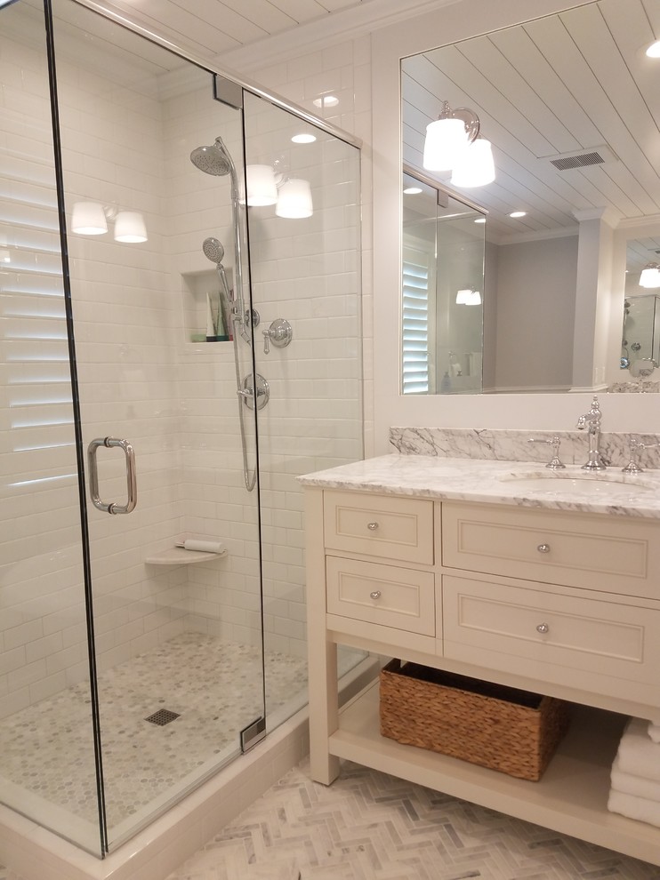 Mid-sized transitional master bathroom in Cincinnati with furniture-like cabinets, white cabinets, a freestanding tub, a corner shower, a two-piece toilet, white tile, subway tile, grey walls, marble floors, an undermount sink, marble benchtops, grey floor and a hinged shower door.