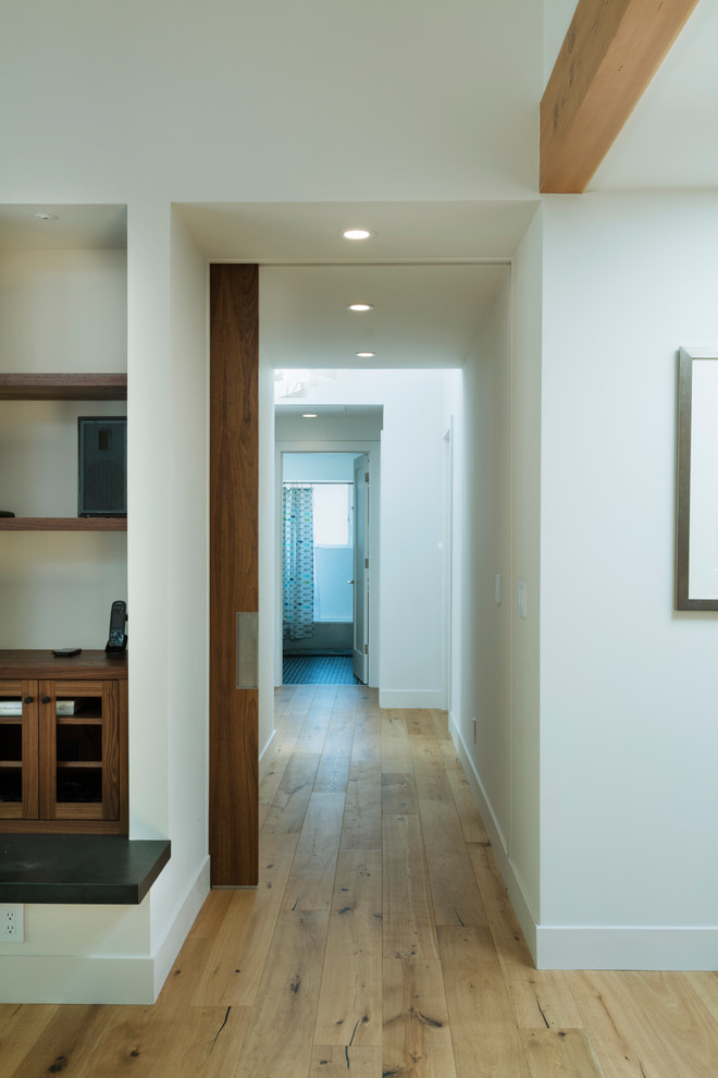 Design ideas for a large modern hallway in San Francisco with white walls and light hardwood floors.