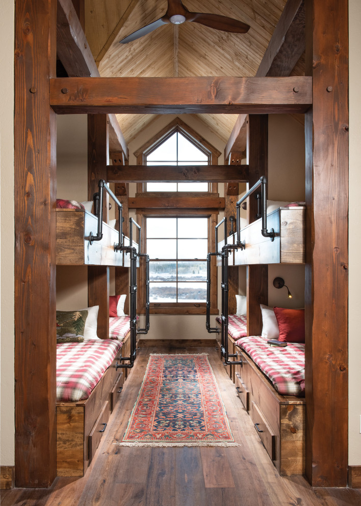 Design ideas for a country gender-neutral kids' bedroom for kids 4-10 years old in Other with beige walls, medium hardwood floors, brown floor, exposed beam, vaulted and wood.