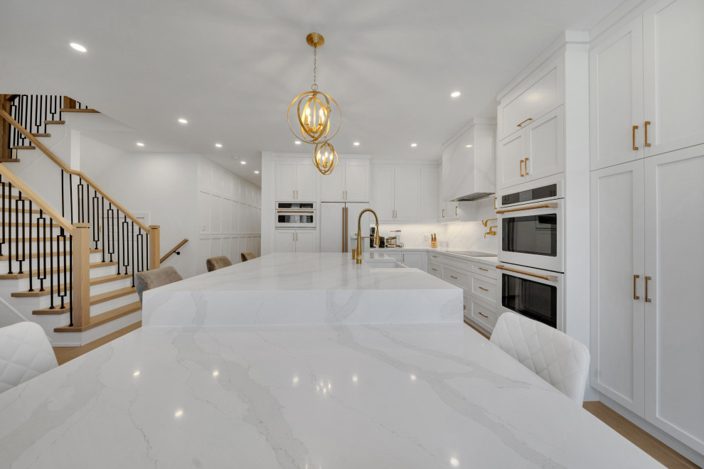 Design ideas for a large contemporary l-shaped eat-in kitchen in DC Metro with a farmhouse sink, shaker cabinets, white cabinets, quartz benchtops, white splashback, engineered quartz splashback, white appliances, medium hardwood floors, with island, yellow floor and white benchtop.