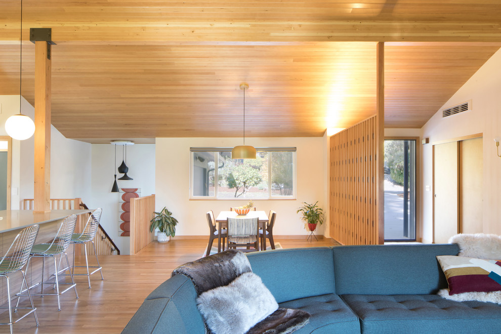 Design ideas for a mid-sized midcentury open concept living room in Seattle with white walls, medium hardwood floors, a standard fireplace, a tile fireplace surround and brown floor.