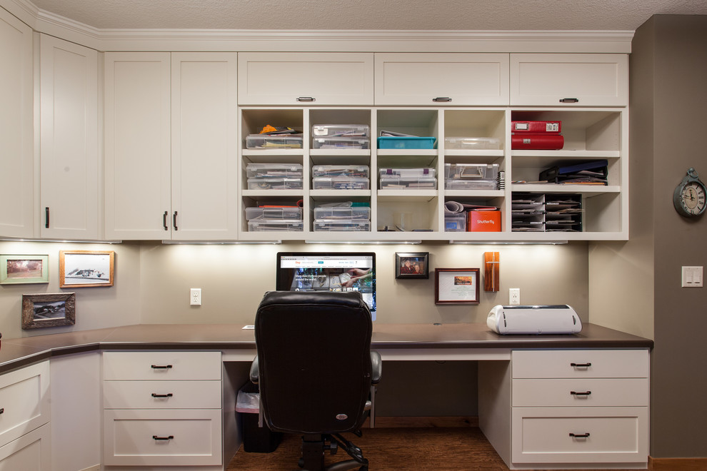 This is an example of a large contemporary craft room in Minneapolis with beige walls, vinyl floors and a built-in desk.