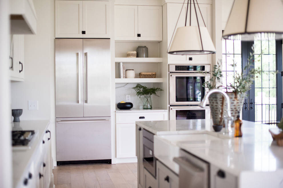 Open concept kitchen - huge transitional u-shaped light wood floor and brown floor open concept kitchen idea in Indianapolis with a farmhouse sink, shaker cabinets, white cabinets, quartzite countertops, white backsplash, marble backsplash, stainless steel appliances and an island
