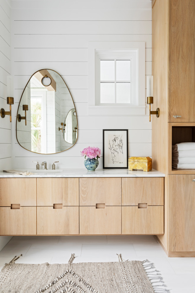 Пример оригинального дизайна: огромная главная ванная комната в морском стиле с плоскими фасадами, светлыми деревянными фасадами, отдельно стоящей ванной, открытым душем, белой плиткой, белыми стенами, полом из керамогранита, монолитной раковиной, мраморной столешницей, белым полом, открытым душем, белой столешницей, сиденьем для душа, тумбой под одну раковину, подвесной тумбой, потолком из вагонки и стенами из вагонки