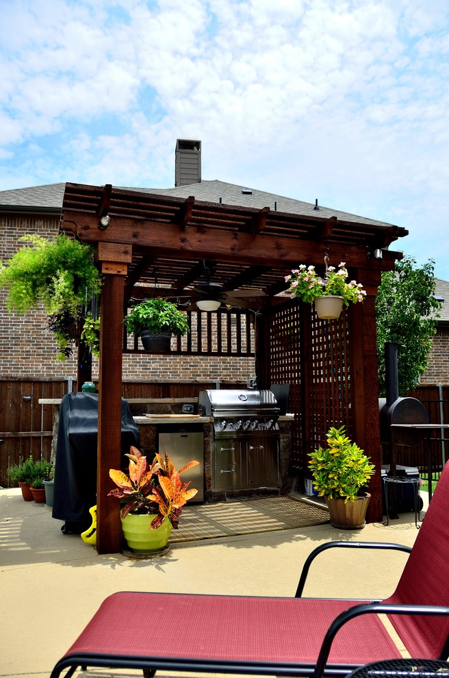 Mid-sized tropical backyard patio in Dallas with an outdoor kitchen, decking and a pergola.