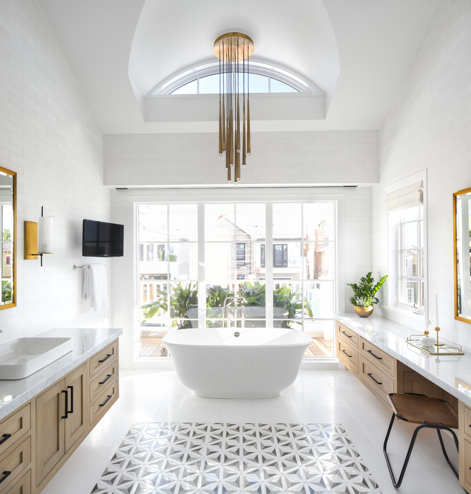 Large modern master bathroom in Orange County with shaker cabinets, light wood cabinets, a freestanding tub, white tile, subway tile, white walls, a vessel sink, marble benchtops and white floor.
