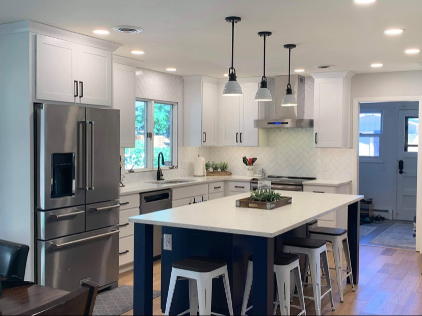 Small transitional l-shaped brown floor eat-in kitchen photo with an undermount sink, shaker cabinets, white cabinets, quartz countertops, white backsplash, ceramic backsplash, stainless steel appliances, an island and white countertops