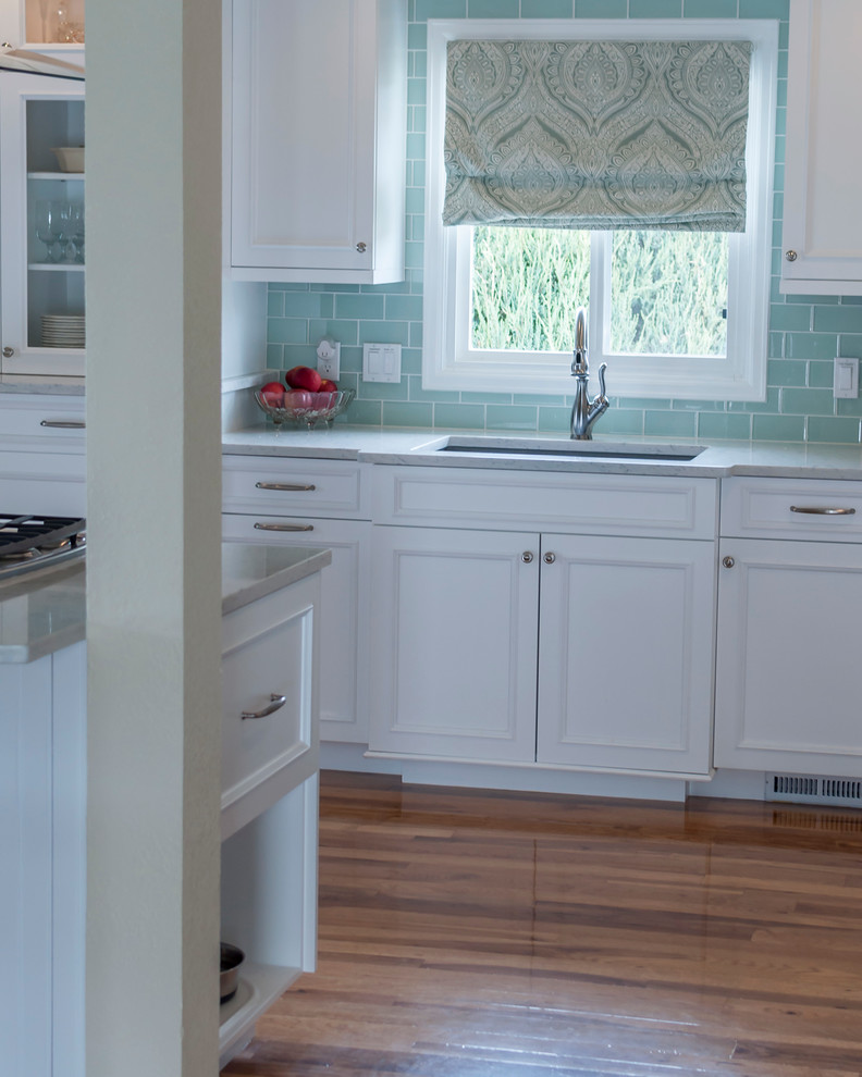 Eat-in kitchen - mid-sized transitional medium tone wood floor eat-in kitchen idea in Denver with a single-bowl sink, flat-panel cabinets, yellow cabinets, quartz countertops, blue backsplash, glass tile backsplash, white appliances and an island