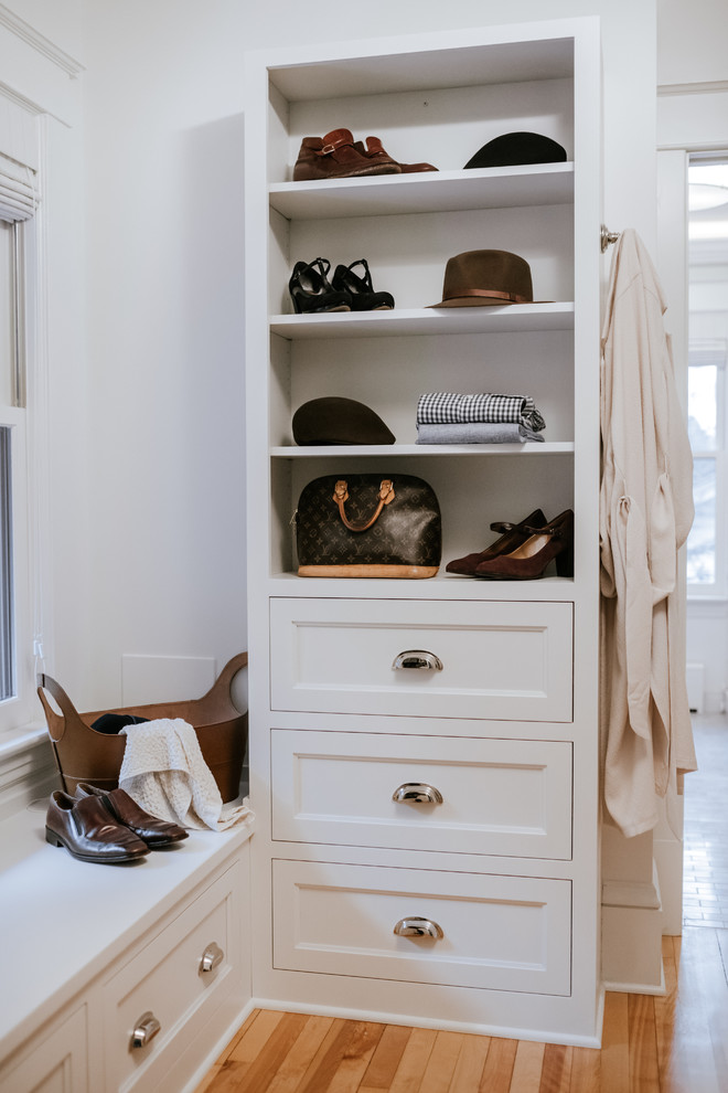 This is an example of a traditional gender-neutral walk-in wardrobe in Minneapolis with white cabinets, recessed-panel cabinets and light hardwood floors.