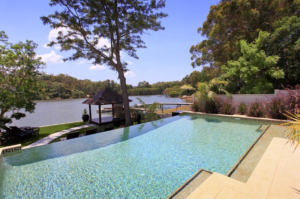 Mid-sized contemporary backyard rectangular infinity pool in Sydney with concrete pavers.