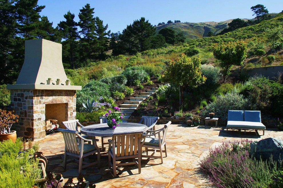 Design ideas for a mid-sized country backyard patio in Seattle with natural stone pavers and no cover.