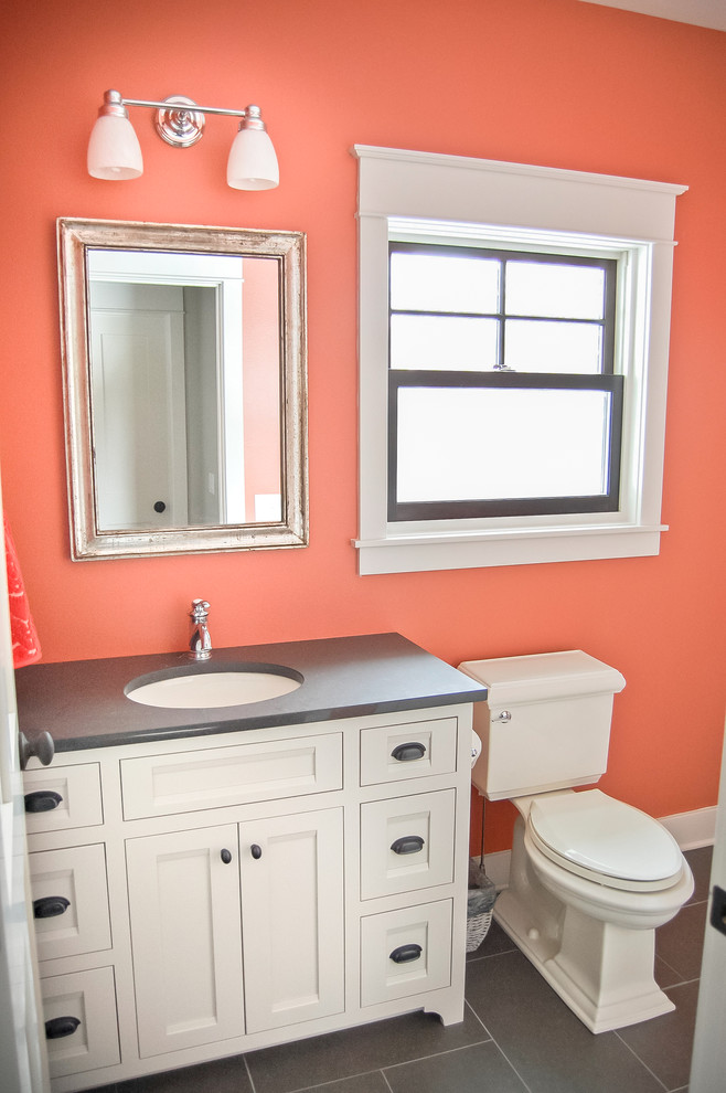 Photo of a mid-sized traditional kids bathroom in Other with furniture-like cabinets, white cabinets, engineered quartz benchtops, a shower/bathtub combo, gray tile, porcelain tile and orange walls.