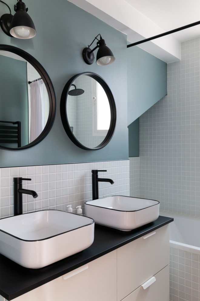 Inspiration pour une salle de bain principale minimaliste de taille moyenne avec une baignoire encastrée, un carrelage blanc, des carreaux de porcelaine, un mur bleu, un sol en carrelage de terre cuite, un lavabo posé, un plan de toilette noir et meuble double vasque.