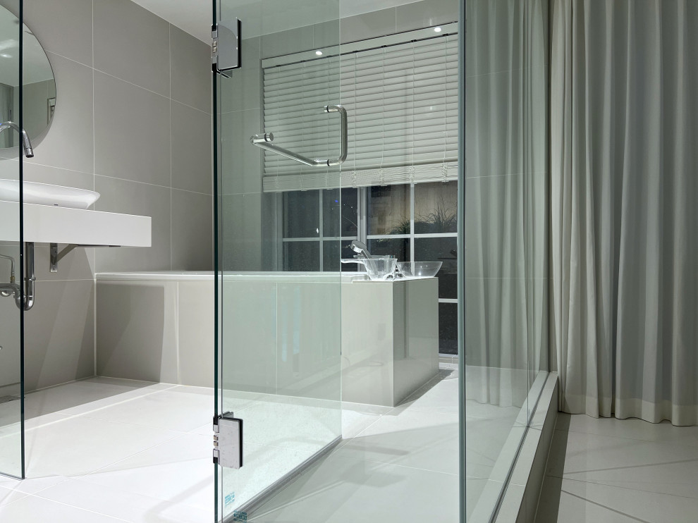 Bild på ett mellanstort funkis vit vitt en-suite badrum, med vita skåp, ett platsbyggt badkar, en dusch/badkar-kombination, grå kakel, klinkergolv i porslin, ett piedestal handfat, grått golv och dusch med gångjärnsdörr