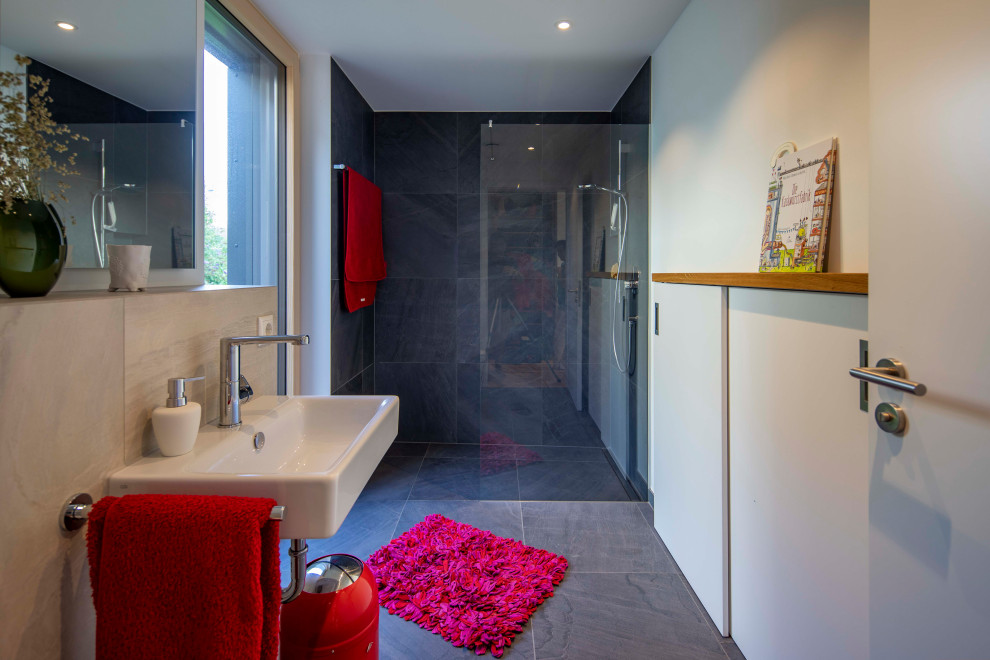 Modernes Badezimmer mit bodengleicher Dusche, grauen Fliesen, Wandwaschbecken, grauem Boden und offener Dusche in München