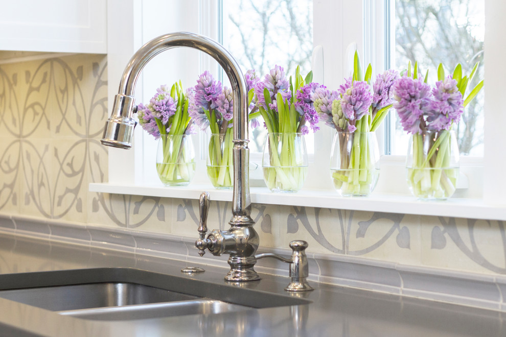 Example of a mid-sized transitional galley medium tone wood floor enclosed kitchen design with a double-bowl sink, recessed-panel cabinets, white cabinets, quartz countertops, beige backsplash, ceramic backsplash, stainless steel appliances and a peninsula