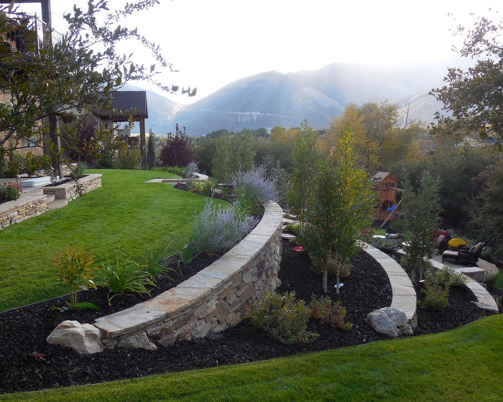 Mid-sized traditional sloped partial sun garden in Salt Lake City with a retaining wall and natural stone pavers.