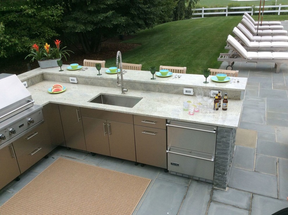 Large traditional backyard patio in New York with an outdoor kitchen, an awning and concrete pavers.