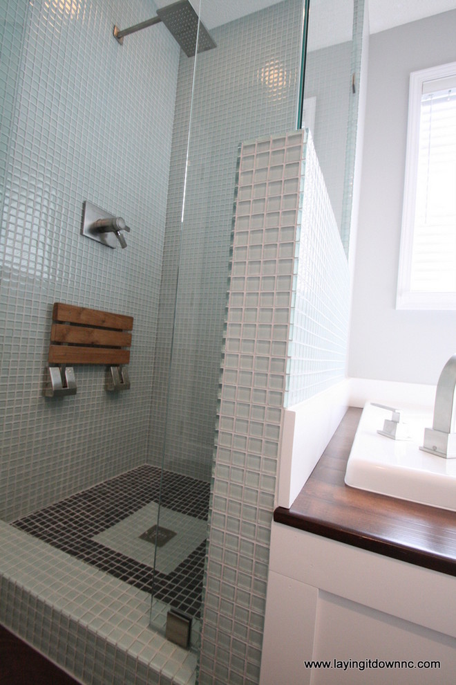 This is an example of a mid-sized contemporary master bathroom in Charlotte with a vessel sink, flat-panel cabinets, white cabinets, granite benchtops, a drop-in tub, a corner shower, a two-piece toilet, green tile, glass tile, grey walls and porcelain floors.
