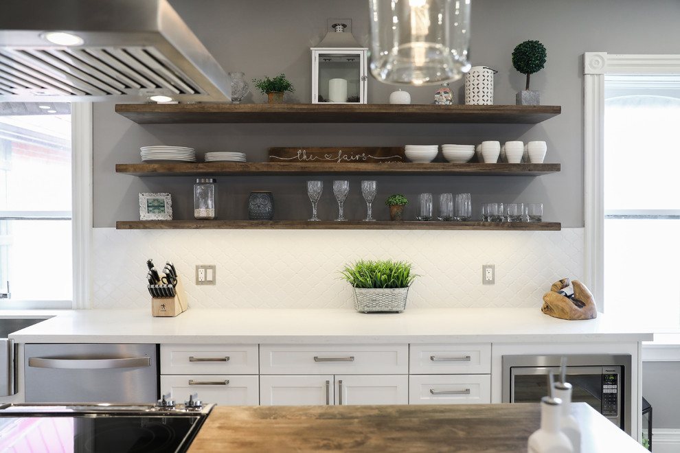 Eat-in kitchen - mid-sized transitional single-wall medium tone wood floor and brown floor eat-in kitchen idea in Other with a farmhouse sink, shaker cabinets, white cabinets, white backsplash, stainless steel appliances, an island and white countertops