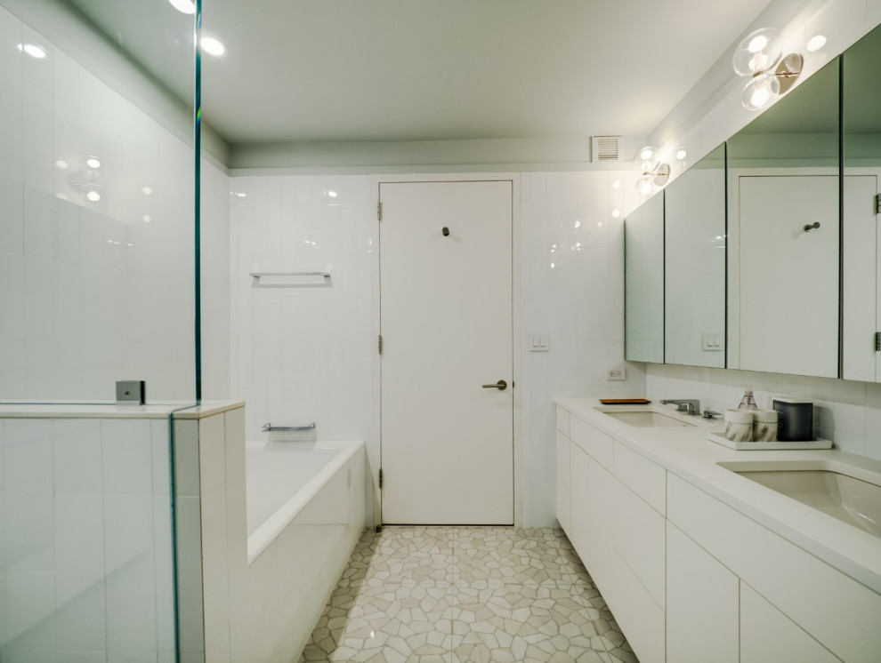This is an example of a medium sized contemporary family bathroom in New York with flat-panel cabinets, white cabinets, an alcove bath, a shower/bath combination, a one-piece toilet, white tiles, porcelain tiles, white walls, terrazzo flooring, a submerged sink, engineered stone worktops, grey floors, a hinged door, white worktops, a single sink and a floating vanity unit.