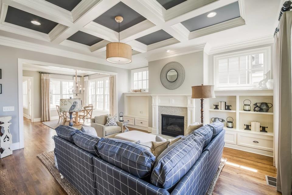 Large open concept family room in Nashville with a library, white walls, medium hardwood floors, a standard fireplace and a plaster fireplace surround.