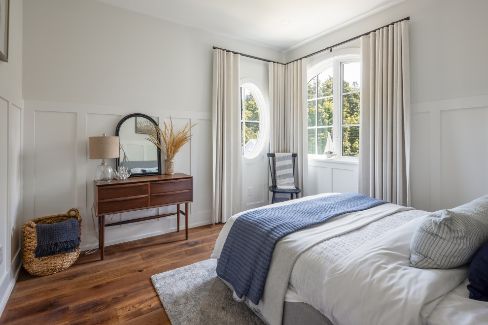 Mid-sized beach style guest medium tone wood floor, brown floor and wall paneling bedroom photo in Vancouver with white walls