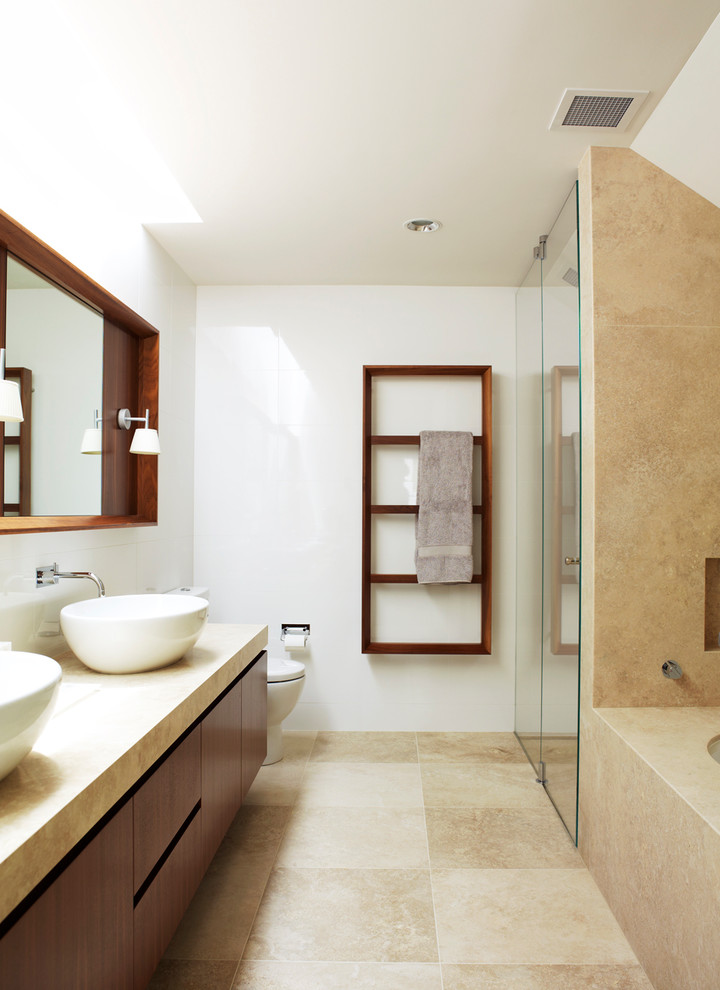 This is an example of a contemporary master bathroom in Sydney with flat-panel cabinets, dark wood cabinets, an alcove shower, a two-piece toilet, beige tile, white walls, a vessel sink, beige floor, a hinged shower door and beige benchtops.