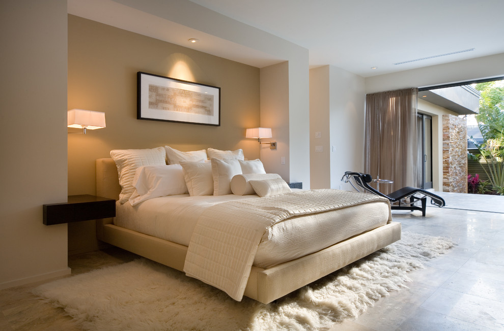 This is an example of a contemporary master bedroom in Orlando with beige walls and travertine floors.
