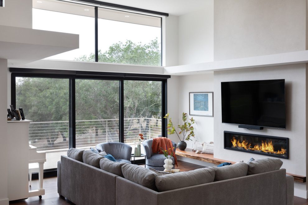 Medium sized modern open plan living room in Other with white walls, medium hardwood flooring, a standard fireplace, a plastered fireplace surround, a wall mounted tv, brown floors and a drop ceiling.