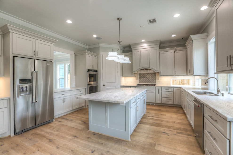 Inspiration for a mid-sized transitional u-shaped light wood floor and beige floor enclosed kitchen remodel in Houston with shaker cabinets, gray cabinets, white backsplash, stainless steel appliances, an island, a double-bowl sink, marble countertops and subway tile backsplash