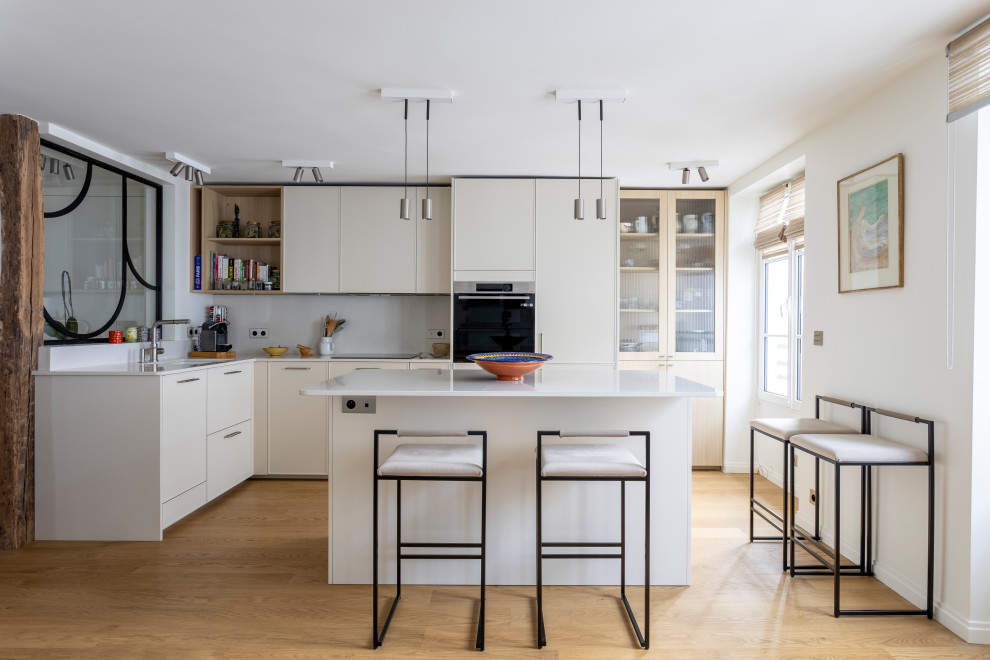 Esempio di una cucina minimal con lavello sottopiano, ante lisce, ante beige, elettrodomestici in acciaio inossidabile, pavimento in legno massello medio, pavimento marrone e top bianco