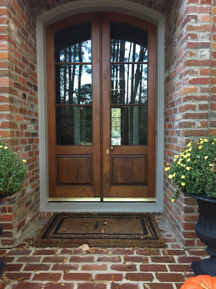 Design ideas for a mid-sized traditional front door in Jackson with red walls, brick floors, a double front door, a dark wood front door and red floor.