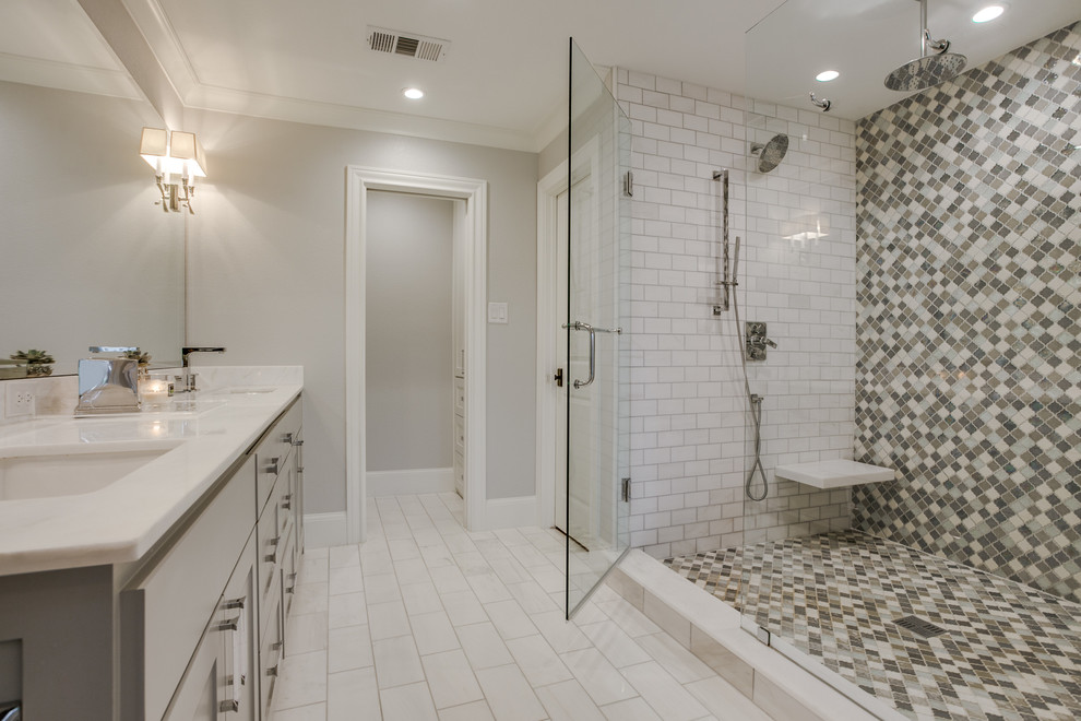 Cette photo montre une grande salle de bain principale tendance avec un placard à porte shaker, des portes de placard grises, une baignoire indépendante, WC séparés, un carrelage blanc, un sol en carrelage de porcelaine, un lavabo encastré, un plan de toilette en marbre et un mur gris.