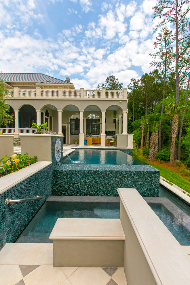 This is an example of a mediterranean custom-shaped infinity pool in Charleston with tile and a hot tub.