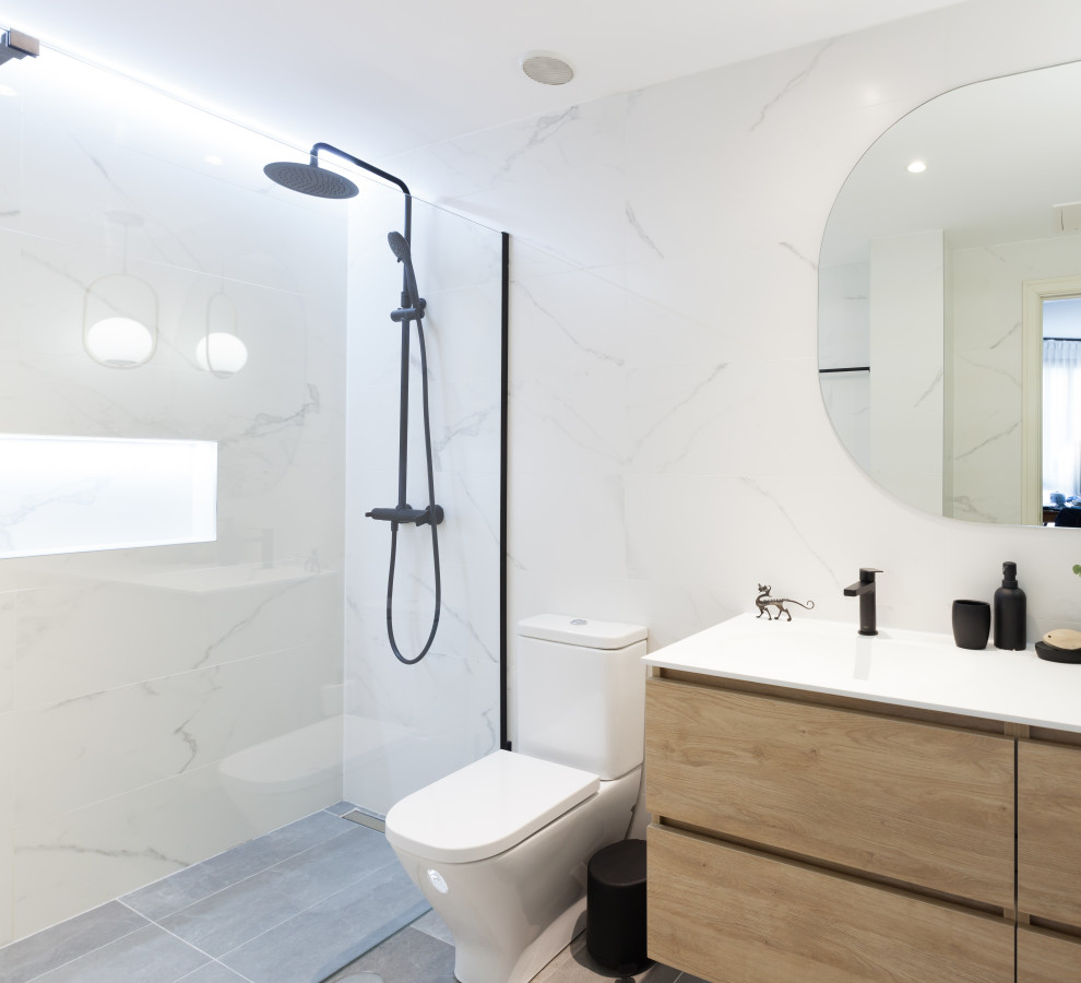 Design ideas for a medium sized contemporary ensuite bathroom in Madrid with freestanding cabinets, white cabinets, a built-in shower, a one-piece toilet, black and white tiles, ceramic tiles, white walls, ceramic flooring, an integrated sink, engineered stone worktops, grey floors, a hinged door, white worktops, a wall niche, a single sink and a built in vanity unit.