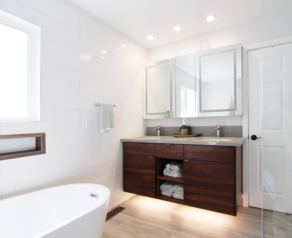 Example of a large transitional master white tile and ceramic tile porcelain tile, gray floor and double-sink freestanding bathtub design with flat-panel cabinets, dark wood cabinets, a one-piece toilet, white walls, an undermount sink, quartz countertops, gray countertops, a niche and a floating vanity