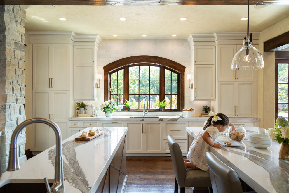 Photo of a large transitional galley eat-in kitchen in St Louis with an undermount sink, recessed-panel cabinets, white cabinets, white splashback, marble splashback, panelled appliances, dark hardwood floors, multiple islands, brown floor, multi-coloured benchtop, exposed beam and quartz benchtops.