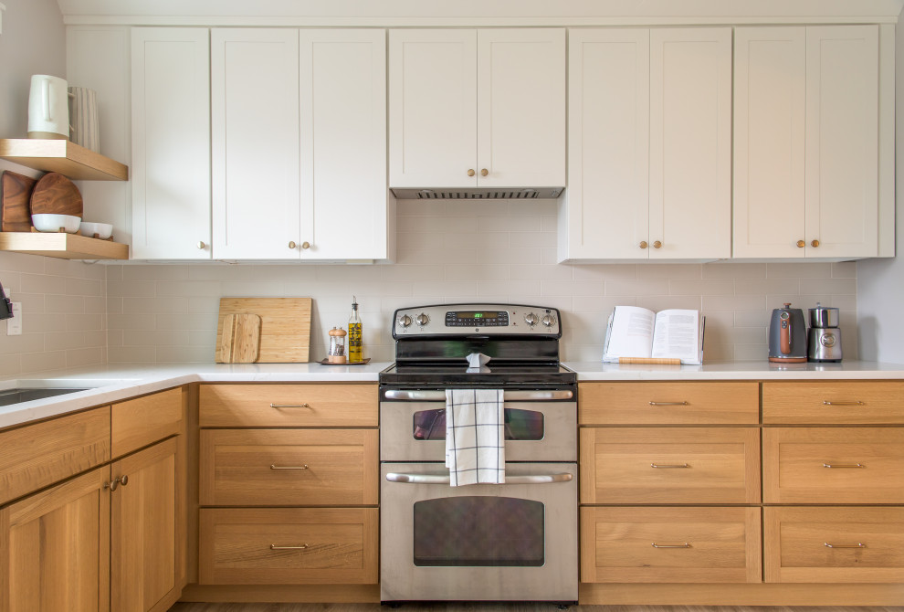 Mid-sized transitional u-shaped light wood floor and brown floor eat-in kitchen photo with an undermount sink, shaker cabinets, white cabinets, white backsplash, subway tile backsplash, no island and white countertops