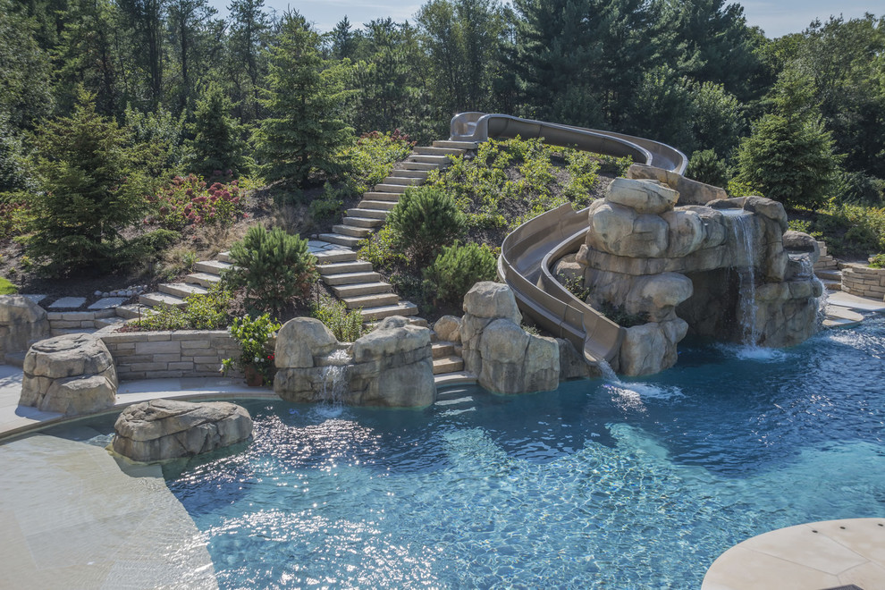 Expansive backyard custom-shaped infinity pool in Chicago with a water slide and natural stone pavers.