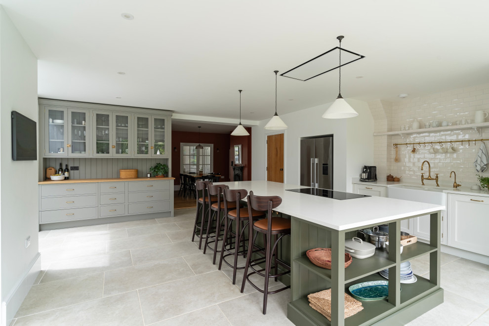 Offene, Große Klassische Küche in grau-weiß mit Landhausspüle, Schrankfronten im Shaker-Stil, grauen Schränken, Quarzit-Arbeitsplatte, Küchenrückwand in Beige, Küchengeräten aus Edelstahl, Keramikboden, Kücheninsel, grauem Boden und weißer Arbeitsplatte in Oxfordshire